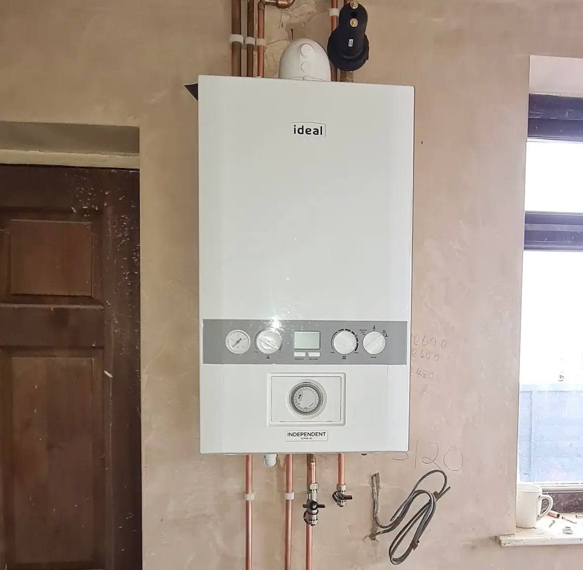 New Ideal combi boiler installed on a plastered wall with copper pipework