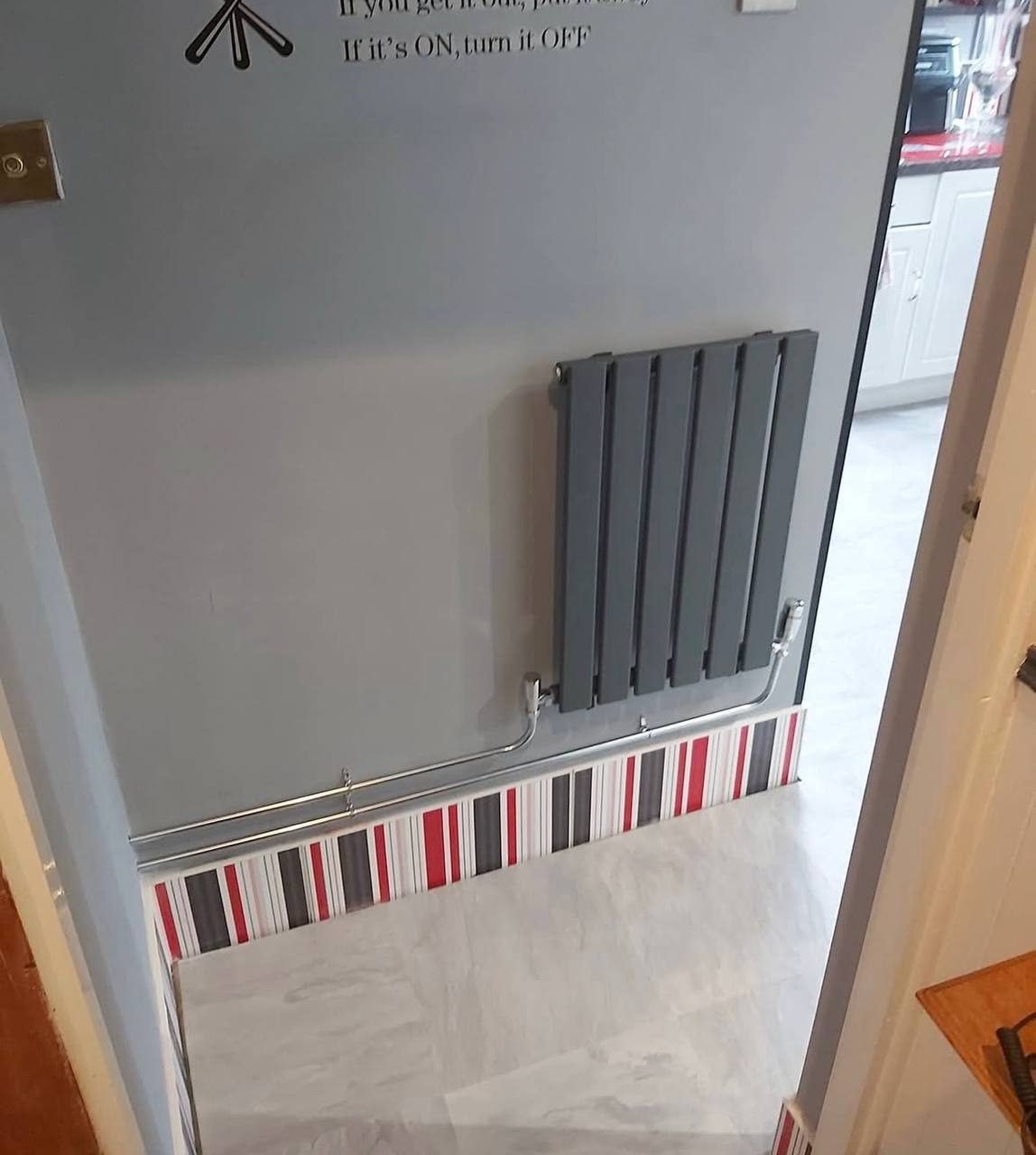Anthracite flat panel radiator with chrome pipework in a hallway