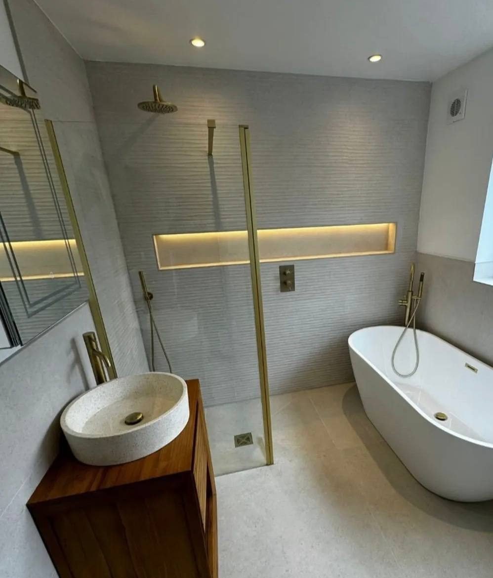 Freestanding bath and walk-in shower with brushed brass taps in a bathroom installation