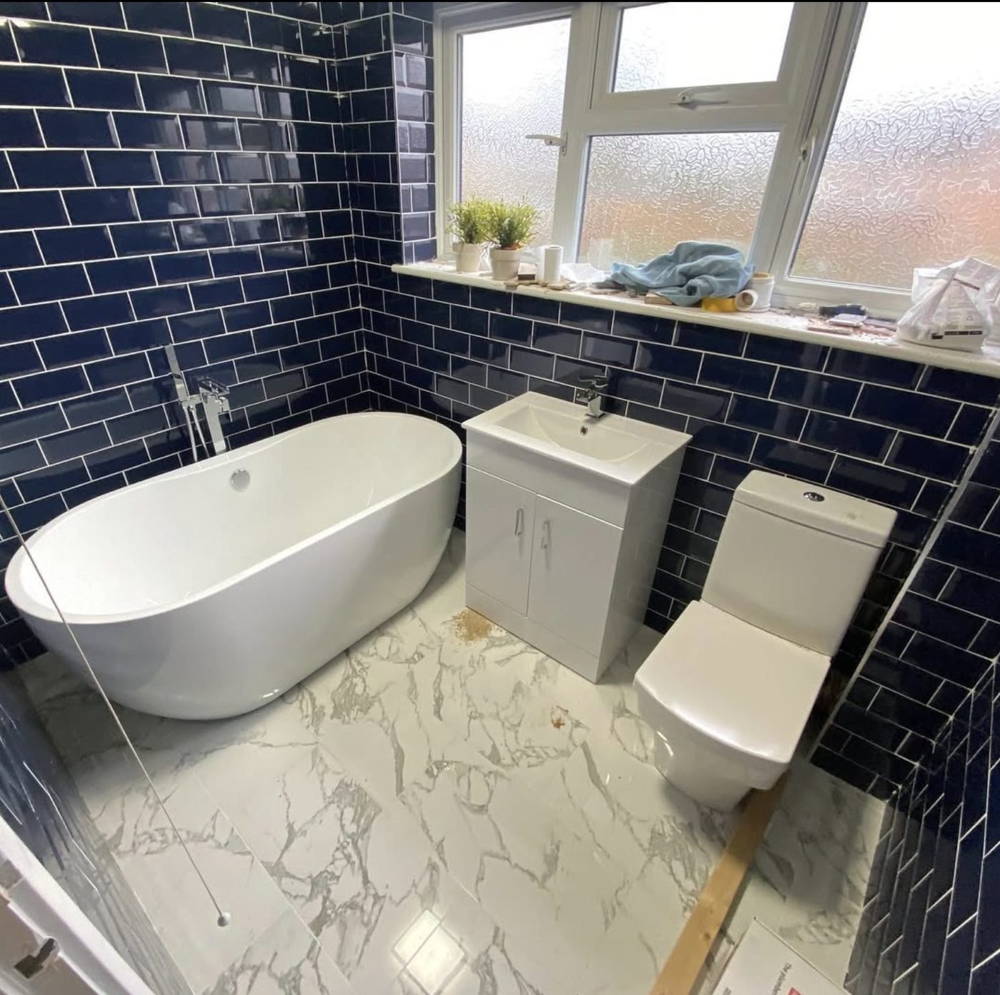 Navy tiled bathroom with a freestanding bath installed by Plumber To The Rescue Sheffield